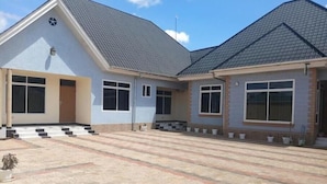 A two-story building with a flat roof, large windows, and a paved courtyard. - Peaceful Central Stay at Pristine Homes (Kilimanjaro Region)