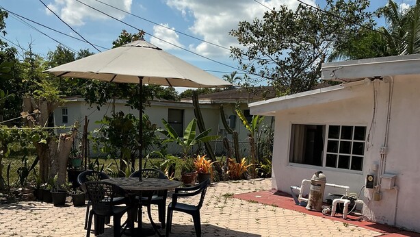 A swimming pool with a tiled edge, a patio area with a table and chairs, and a covered outdoor seating area. - Cozy Miramar 1 Bedroom with POOL for vacation, travel nurse short, longterm rent (Miramar)