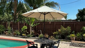 A patio area with a pool, a table with chairs, and an umbrella. - Cozy Miramar 1 Bedroom with POOL for vacation, travel nurse short, longterm rent (Miramar)
