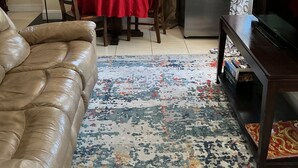 A living room with a leather sofa, a red dining table, a kitchen area with a refrigerator, and a TV on a wooden stand. - Cozy Miramar 1 Bedroom with POOL for vacation, travel nurse short, longterm rent (Miramar)