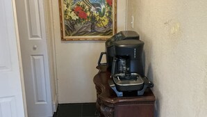 A hallway with a coffee maker on a wooden cabinet, a door, and a framed floral painting on the wall. - Cozy Miramar 1 Bedroom with POOL for vacation, travel nurse short, longterm rent (Miramar)