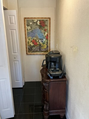 A hallway with a coffee maker on a wooden cabinet, a door, and a framed floral painting on the wall. - Cozy Miramar 1 Bedroom with POOL for vacation, travel nurse short, longterm rent (Miramar)