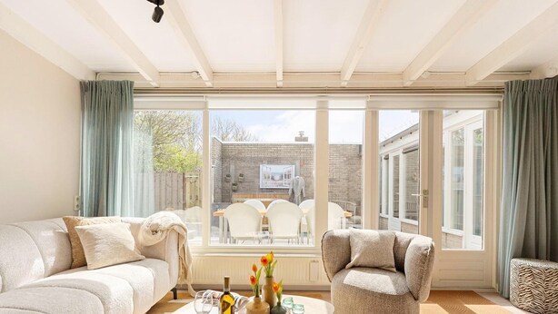 A spacious living room with a large window, a sofa, a chair, and a coffee table. - Fantastic Holiday Home Near hot tub (Sint Maartensvlotbrug)