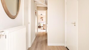 A hallway with a white door, a radiator, and a mirror on the left wall. - Fantastic Holiday Home Near hot tub (Sint Maartensvlotbrug)