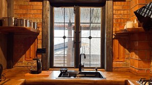 Una cocina con encimera de madera, un lavamanos y una ventana con vistas a árboles.