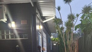 A black building with a gravel pathway, a wooden bench, and potted plants. - Quaint cottage in Glenwood, Durban (Durban)