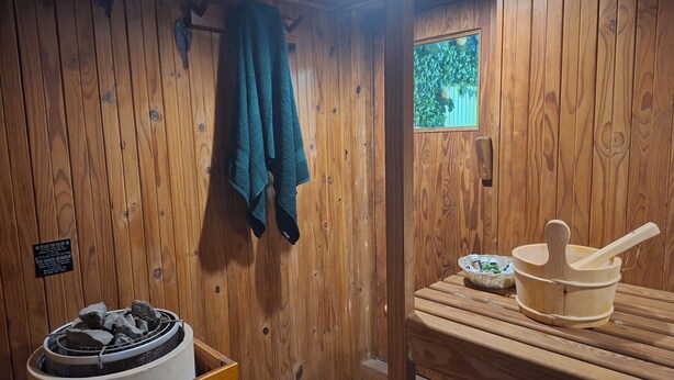A wooden cabin interior with a stone fire feature, a small window with a view, and a wooden table with a bowl and a wooden utensil. - Quaint cottage in Glenwood, Durban (Durban)
