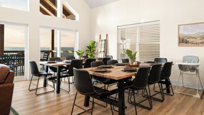A dining area with a wooden table, black chairs, and large windows offering a view.