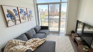 A modern living room with a grey sofa, a TV, and artwork on the wall.