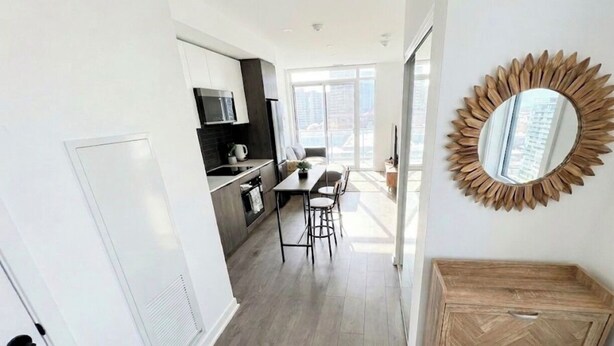 A modern kitchen with a dining area, a wooden cabinet, and a decorative mirror.