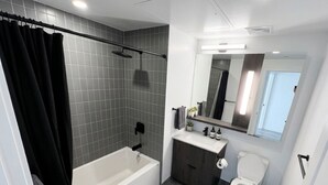 A modern bathroom with a bathtub, toilet, vanity, and a shower area.