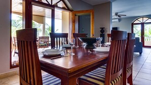 A dining area with a wooden table and chairs, a large bowl, and a view of the outdoors. - Beachfront Combo Villa with Pool & Spacious Layout (North Placencia)