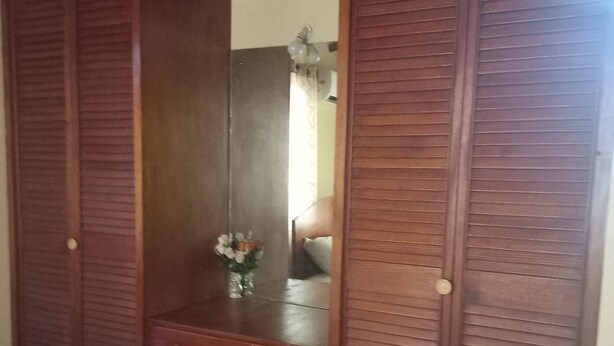 A wooden wardrobe with a mirror, a dresser, and a bed with a green blanket. - Fabulous 1-bedroom apartment with AC in Saint Michael (Saint Michael)