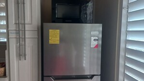 A stainless steel refrigerator with a note attached, a microwave above it, and a white cabinet to the left. - Fabulous 1-bedroom apartment with AC in Saint Michael (Saint Michael)