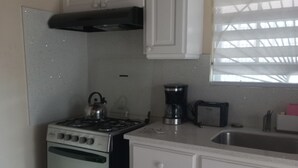 A kitchen with white cabinets, a stove, a coffee maker, and a window with blinds. - Fabulous 1-bedroom apartment with AC in Saint Michael (Saint Michael)