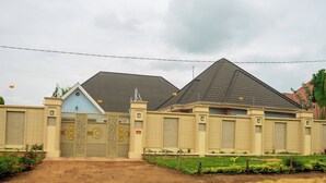 Un bâtiment à deux étages, doté d’une entrée fermée par un portail, d’une porte bleue et d’un toit en pente.