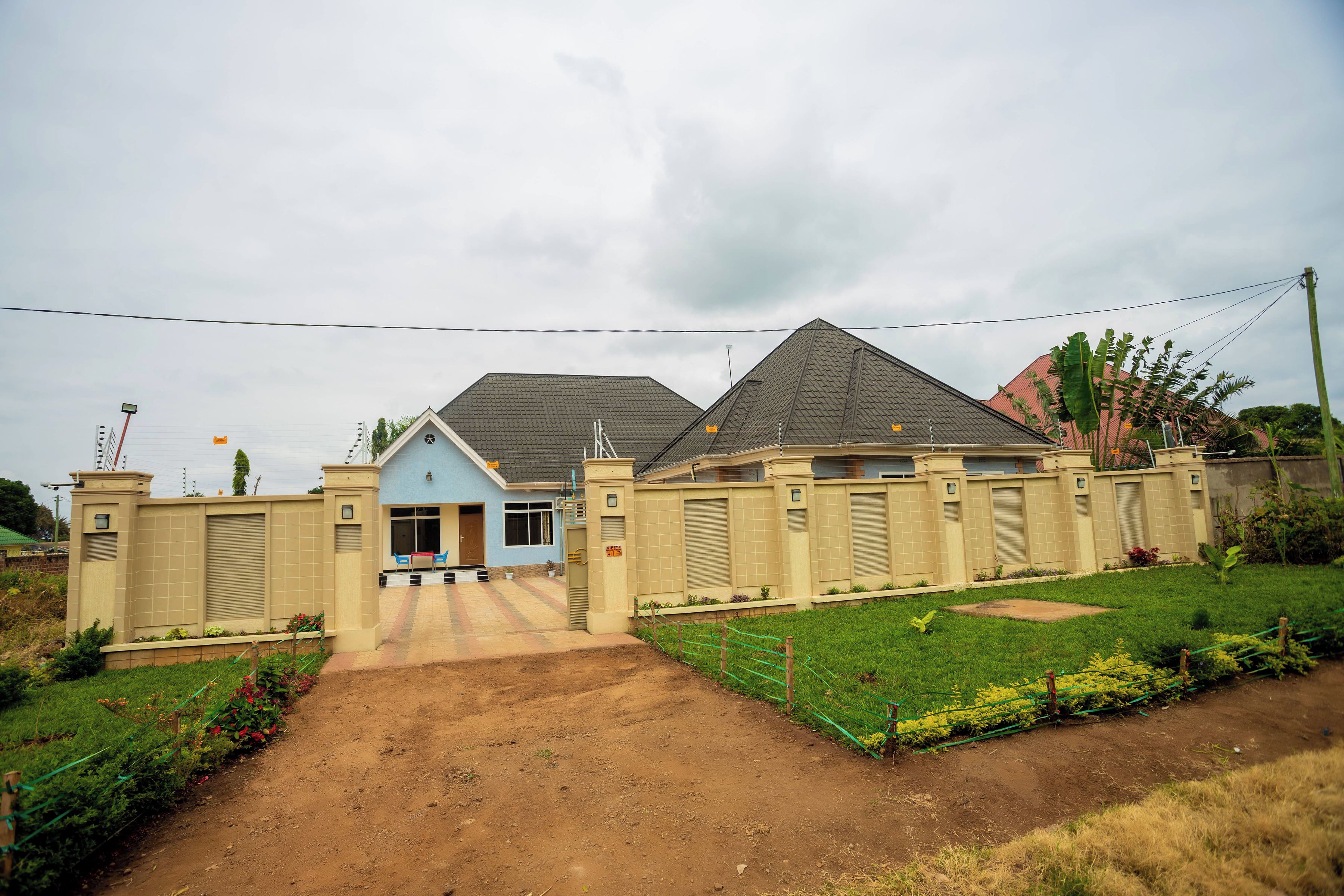 A residential building with a gated entrance, a paved driveway, and a well-maintained lawn.