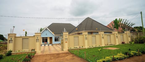 A residential building with a gated entrance, a paved driveway, and a well-maintained lawn.