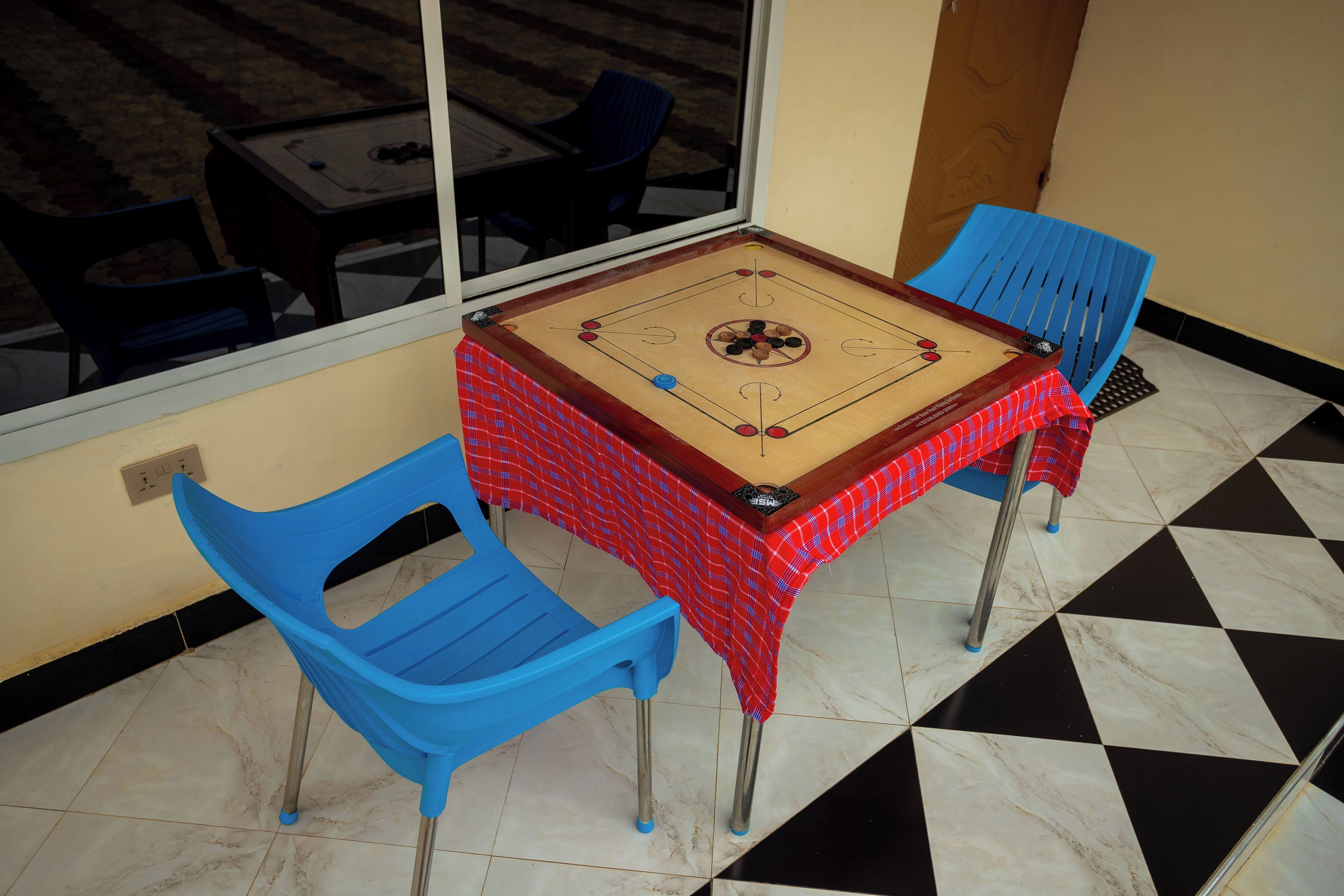 Um quarto com uma mesa de futebol de mesa, duas cadeiras azuis e piso xadrez.
