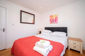 Une chambre à coucher avec un lit, une table de chevet, une commode, un miroir et un tableau accroché au mur.