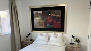 A bedroom with a bed, a nightstand, a lamp, a framed abstract painting, and a window with curtains. - Your own little house.#D Pet-Friendly (Phoenix)