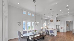 A spacious kitchen with modern appliances, a dining area with a large table and chairs, and a bright, open layout with natural light. - Luxury Beachfront Ocean Views Pool Access Sleeps 15 (Bolivar Peninsula)