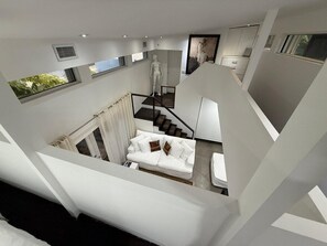 A modern interior with a white staircase, a white sofa with cushions, and a minimalist design. - Coconut Grove Fashion Loft · Pool & Backyard · Walkable (Miami)