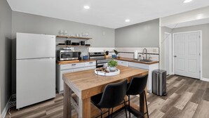 A modern kitchen with a central island, white appliances, and a small trash bin. - Infrared Sauna, Firepit, Kayaks, Walk 2 Launch, Authentic WI Lake Life (Poynette)