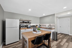 A modern kitchen with a central island, white appliances, and a small trash bin. - Infrared Sauna, Firepit, Kayaks, Walk 2 Launch, Authentic WI Lake Life (Poynette)