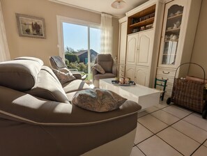 A living room with a sofa, armchairs, a coffee table, and a cabinet with dishes. - Family villa with sea views - Morgat hills (Crozon)