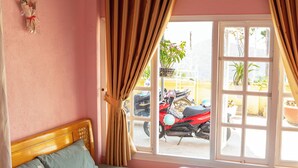 Una habitación con cama, ventana con cortinas y vistas al exterior.