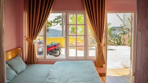 Una habitación con cama, cortinas y ventana con vista a una motocicleta y edificios.