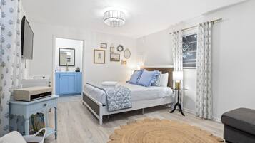 Un dormitorio con cama, mesita de noche, lámpara y una pared decorada con cuadros.