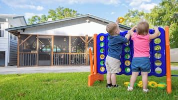 Two children playing on a playground with a building in the background.