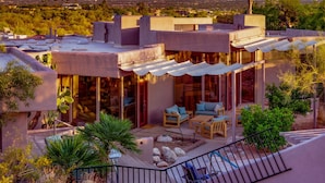 Une maison moderne dotée d’un patio, d’un espace salon extérieur et offrant une vue sur les montagnes.