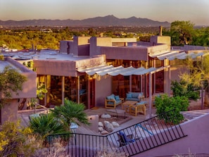 Una casa moderna con un patio, mobiliario exterior y vistas a la montaña.