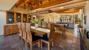 Une pièce spacieuse avec un plafond en bois, un coin repas équipé d’une table de billard et une vue sur l’extérieur.