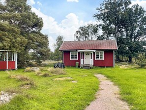 A red house with a porch, a gravel path leading to it, and a small shed to the left. - 4 Person Holiday Home in Morlunda (Mörlunda)