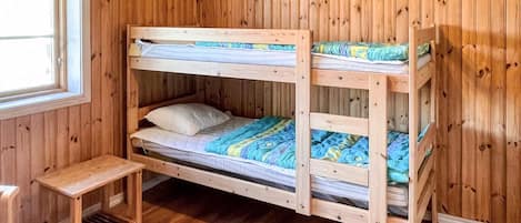 A bunk bed with a small table and a window with a curtain.