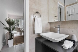 A modern bathroom with a large white sink, a towel rack, and a mirror above the sink. - Coastal Beach Retreat, Heated Pool, Walk to Beach, Water Taxi (Pompano Beach)