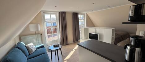 A modern apartment with a living area, kitchenette, and a balcony.