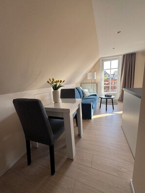A modern apartment with a dining area, a sofa, and a view of the outside. - Vacation Rental Near the Beach with a Balcony in the Town Center (Ahrenshoop)