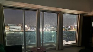 A room with large windows, a round table, and two chairs. - Central Suites Tower T&T Rentals (Santo Domingo)