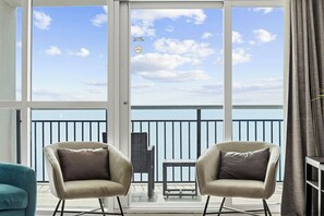 Ein Balkon mit zwei Stühlen, einem kleinen Tisch und Blick aufs Meer.