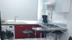 A compact kitchen with a washing machine, a gas stove, and a sink. - Luxury & Fully Equipped | Safe & Terrace | All Amenities within Walking Distance (Tunis)