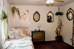 A bedroom with a bed, bedside table, dresser, and decorative mirrors.