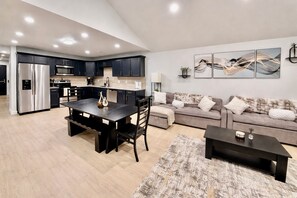 A modern kitchen with dark cabinets, a stainless steel refrigerator, and a dining area with a dark table and chairs. - World Cup Ready! Spacious - W&D - Parking - Fast Wi-Fi (Independence)