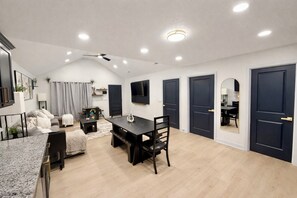 A modern living room with a dining area, a TV mounted on the wall, and a ceiling fan. - World Cup Ready! Spacious - W&D - Parking - Fast Wi-Fi (Independence)