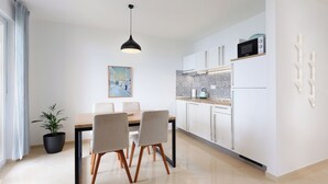 Una cocina moderna con armarios blancos, un microondas y un comedor con mesa y sillas.