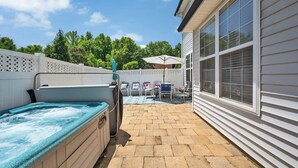Un patio trasero con un jacuzzi, mobiliario exterior y una casa.